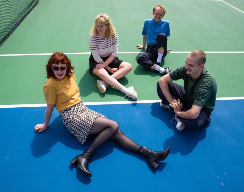 Band pic of Pip blom sitting on a tennis court