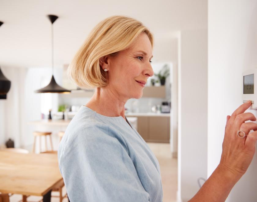 A woman adjusting a room thermostat