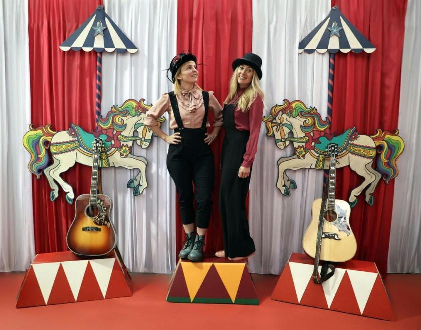 Sounds of the Sirens - two women in dungarees stnading on circus-style rostra next to their guitars