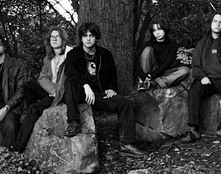 Black and white phot of a band sitting in a woodland