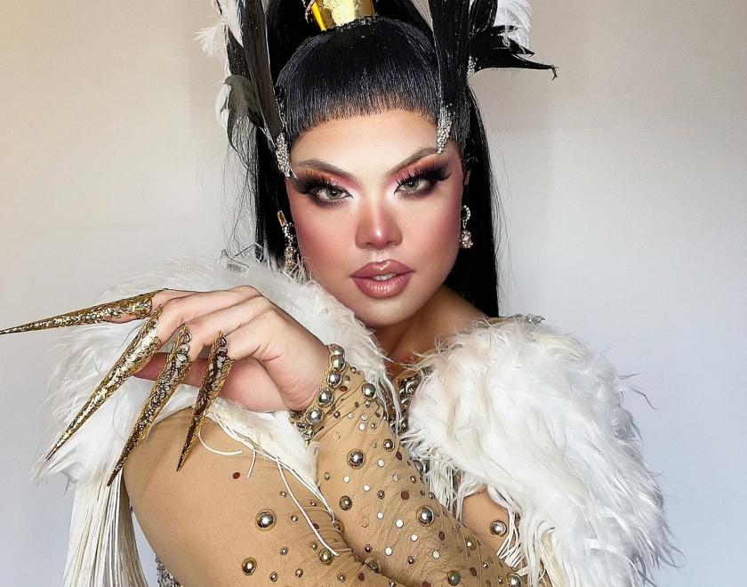 Drag queen Sum Ting Wong in an elaborate gold outfit with feathers and talon-like nails