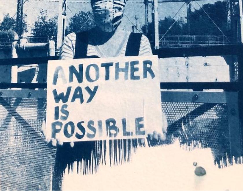 blue print of a woman holding a banner saying another way is possible