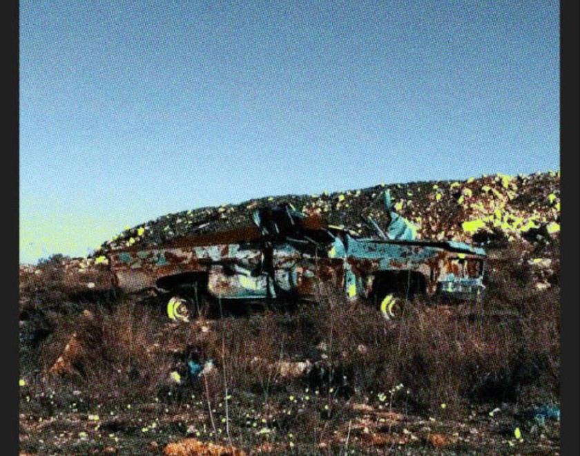 Album cover of blue sky over a burned out car in scrubland