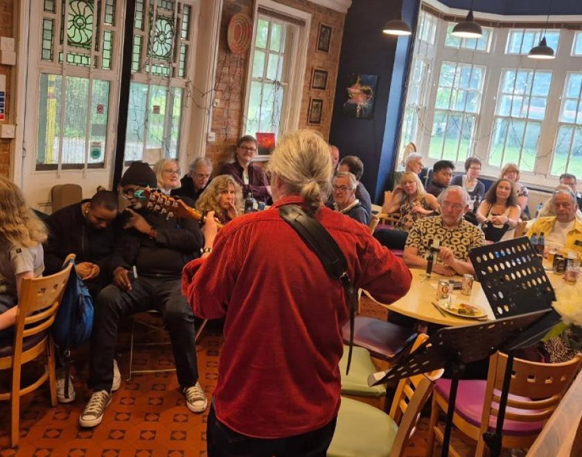 The back of a performer facing the audience at Tut's Open Mic night