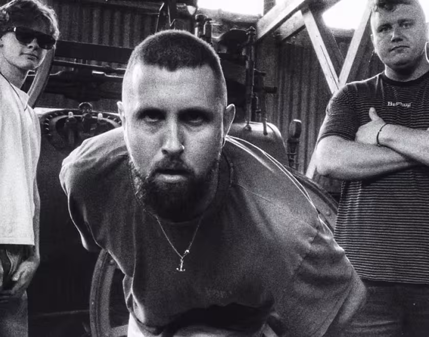 Musicians Wilswood Buoys, three white men standing in front of some industrial equipment